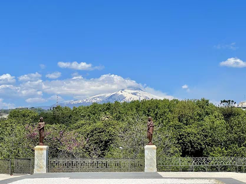 L'Etna innevato visto dal giardino di Villa Bellini, oltre le statue e la ringhiera in ferro